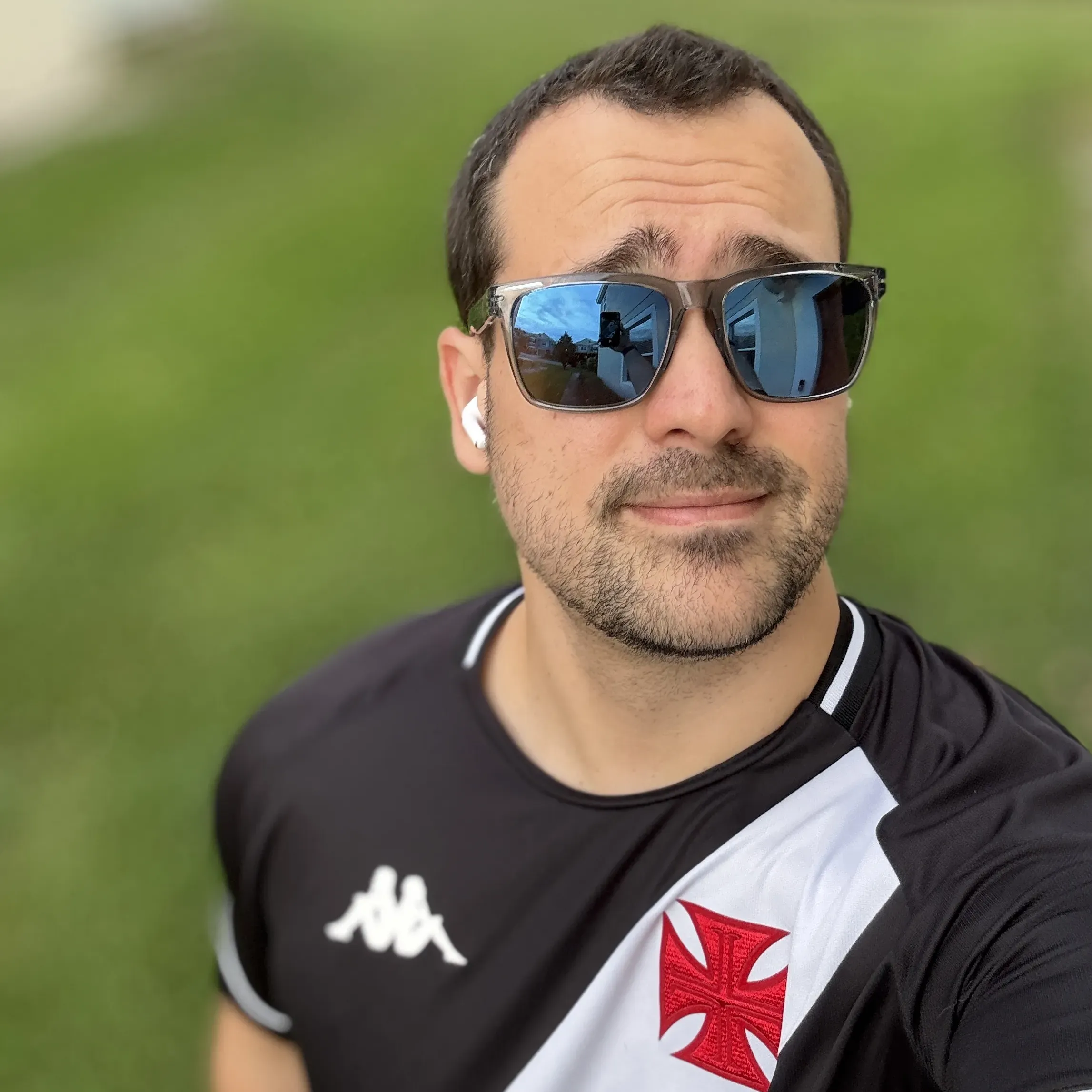 William smiling outdoors wearing sunglasses and a black sports jersey