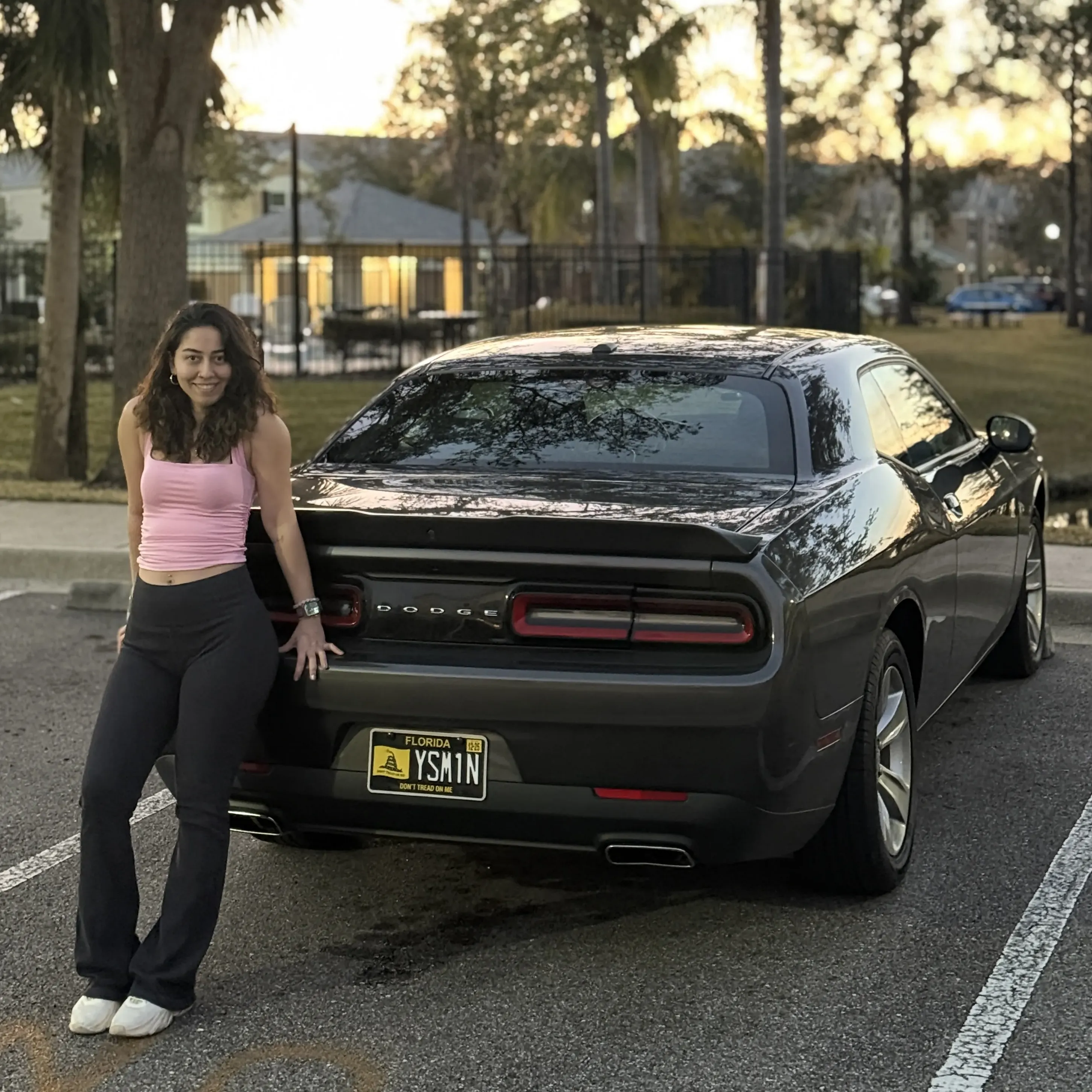 Yasemin standing next to a Dodge Challenger at sunset